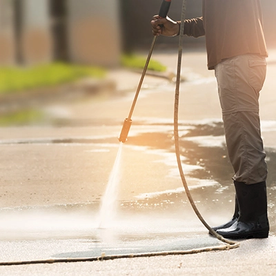 Green Pro professional performing soft wash cleaning on a residential sidewalk